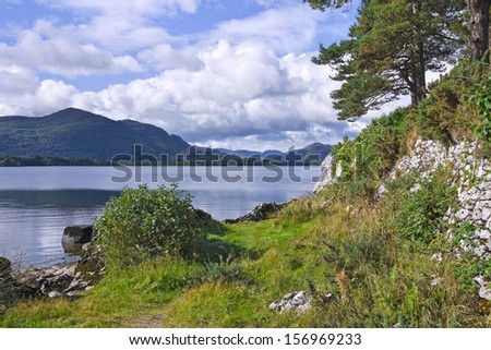 Torc Mountain and the Eagle's Nest Rock from a grassy path by the shore of Lough Leane, the Lower Lake, Killarney, Ireland.
