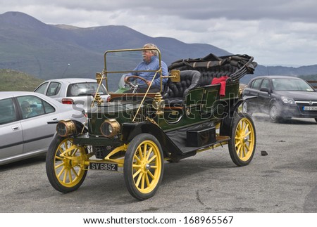 CO. KERRY, IRELAND - JULY 11 2006: The proud owner of an elegant vintage car from the Edwardian era drives off from a roadside car park in the Kerry mountains.