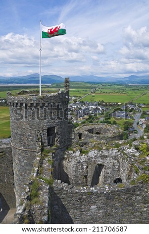 The Welsh flag flutters proudly in the breeze on top of Harlech castle, North Wales, with the mountains of Snowdonia in the background.