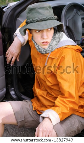 Young girl sitting at a car and looking for something