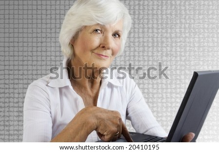 Gracious senior lady with laptop on grey background