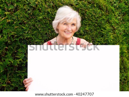 Beautiful senior woman holding blank board with space for text