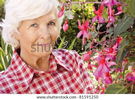 Senior woman portrait, outdoor, in front of the garden ,beside a beautiful flower,smiling to camera