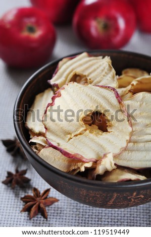Dried apples chips in ceramic bowl with fresh red apples on table. Small shallow DOF.