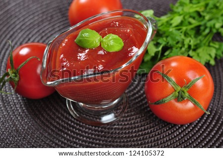 Tomato sauce in a glass gravy boat with fresh tomatoes and basil