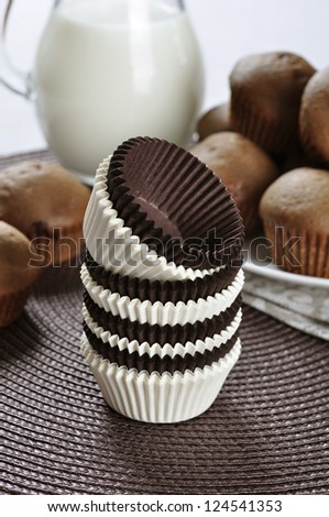 Brown and white cupcake cases with chocolate cupcakes on dark background