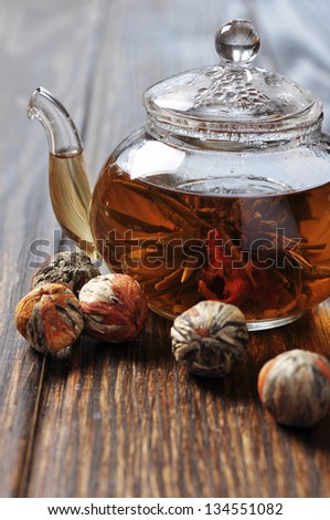 Chinese flowering tea in glass teapot on wooden background