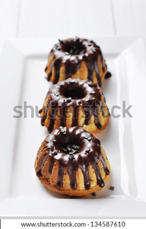 Cake with melted chocolate icing on white dish on wooden background