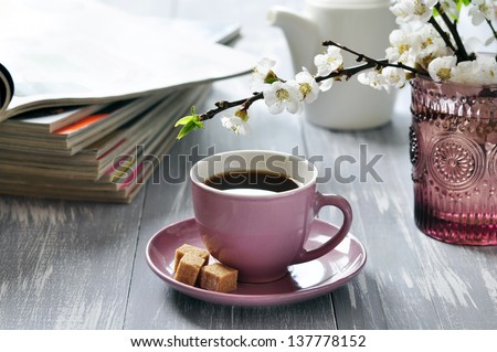 Cup of coffee  with branches of blooming cherry on wooden background