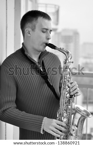 handsome young man playing on saxophone outdoor