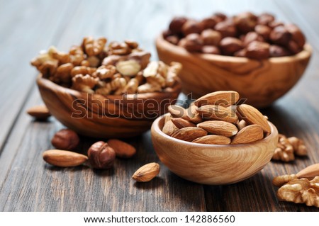 Almonds, walnuts and hazelnuts in wooden bowls  on wooden background