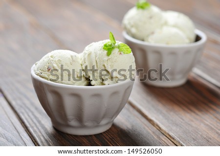 Vanilla ice cream with mint in ceramic bowl on wooden background
