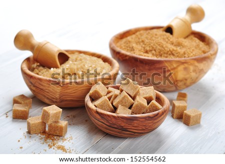brown and white sugar in wooden bowls closeup