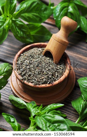 Dry basil in wooden bowl and fresh basil on wooden background