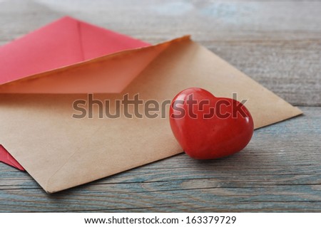 Brown envelop with stone heart on wooden background