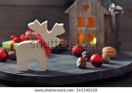 Christmas decoration in shape of elk with lantern on wooden background