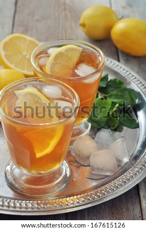 Ice tea in glass with lemon and mint on metal tray
