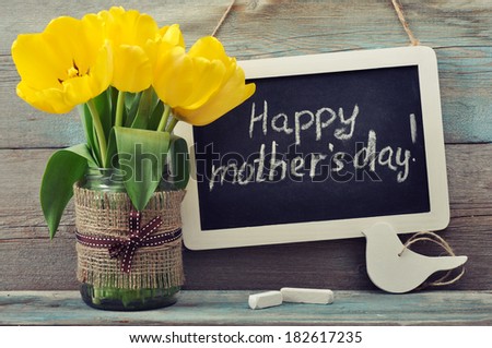 Beautiful tulips bouquet with blackboard and chalk on wooden background