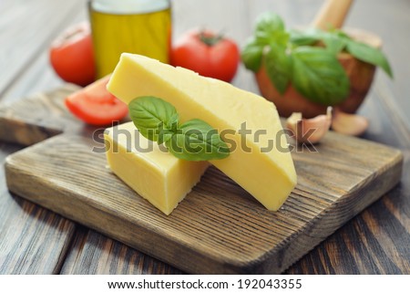 Hard cheese with basil on wooden cutting board