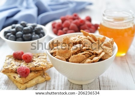 Whole-grain flakes in bowl with fresh berries on light background
