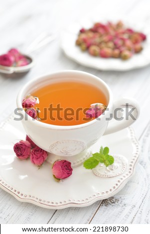 Tea rose flowers  and cup of tea on wooden background