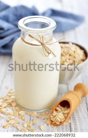 Oat milk in bottle on white wooden background. Vegan and vegetarian milk concept.