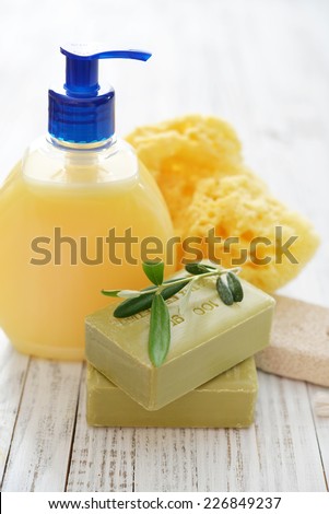 Shower gel with  olive soap and bath sponge on wooden background. The words on soap translates as \