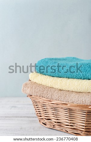 Stack of bath towels  in a wicker basket on a light background