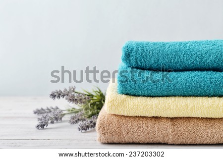 Stack of bath towels with lavender flowers on light wooden background closeup