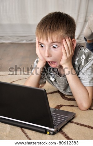 Boy watching scary movie on a laptop at home