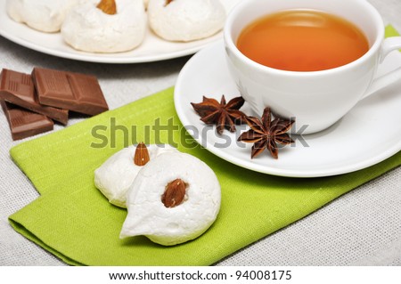 Homemade meringues with almond and cup of tea drink, shallow dof. Focus on meringues.
