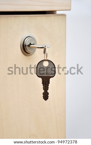 key in lock of wooden desk drawer, closeup