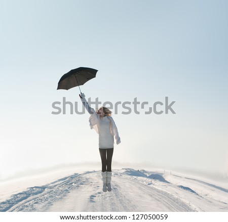 beautiful woman flying with umbrella on road in winter