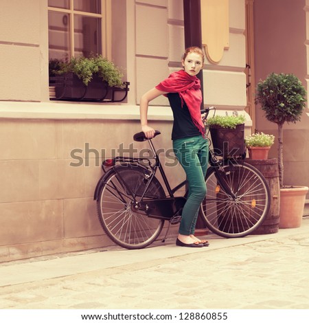 beautiful girl with a bicycle on the street of the old town