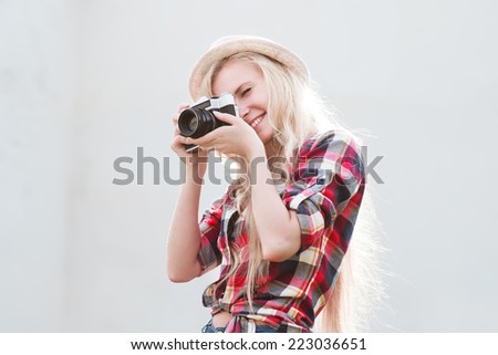 Beautiful smiling sexy blonde with a vintage camera in a hat on the street on a sunny warm day