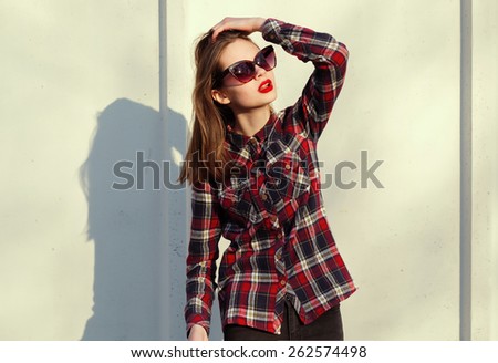 hipster girl with red lips in sunglasses on background of a wall in the city