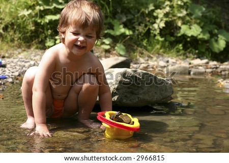 Kid playing with stones and water by the mountain river.