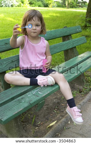 little, cute girl making soap bubbles on a summer day