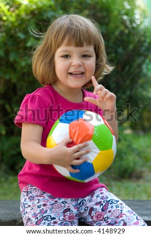 little, cute girl with colorful football outdoors
