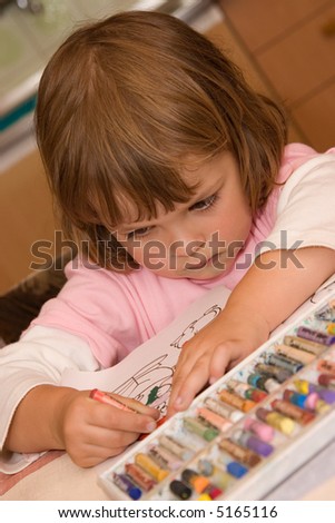 little, cute girl drawing with colorful pastels