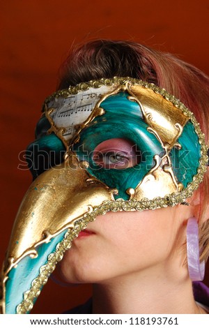 Beautiful young woman in a green and gold mysterious venetian mask