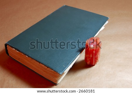 old close book with candle end on paper background