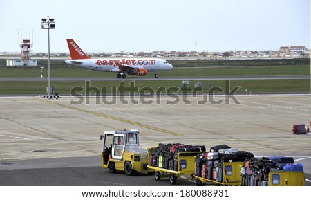 FARO,PORTUGAL-MARCH 3,2014; EasyJet plane ready for take off at Faro airport while at foreground at platform luggage of passengers are transported by a small trailer.March 3, 2014 Faro, Portugal