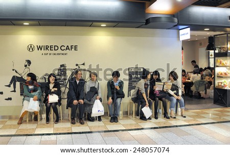 KYOTO, JAPAN-NOVEMBER 9, 2014; People sitting and waiting in line to enter a cafe in the shopping center of the Central Station building.November 9, 2014 Kyoto, Japan