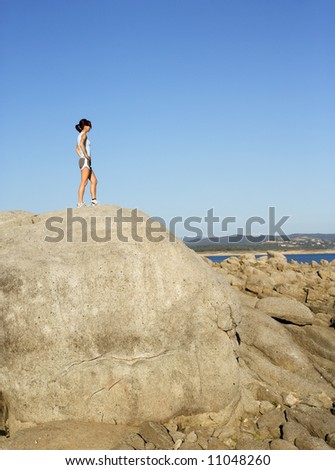 A woman stops to enjoy the view after climbing to the top of a rock