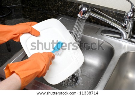 A person scrubs a dish in the kitchen sink