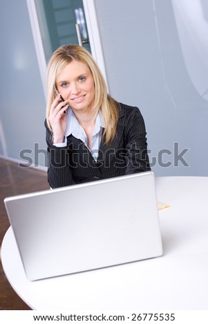 Business Woman on cell at desk in modern office