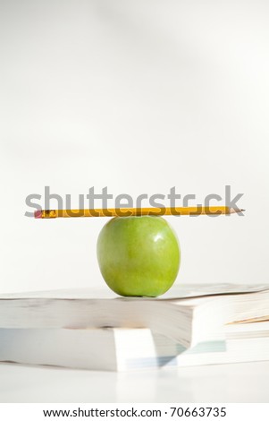 A Pencil on top of an Apple and books