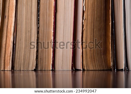 Vintage old books on a wooden table top  against a brick wall