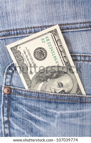 Pocket money. New 100$ in hip pocket of worn blue jeans close-up.